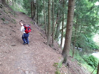 Bambina su sentiero nel bosco, a destra scorre un torrente