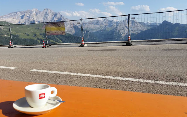 Illy Espresso auf Biertisch mit Bergaussicht und Bauzaun auf dem Sellajoch in Südtirol