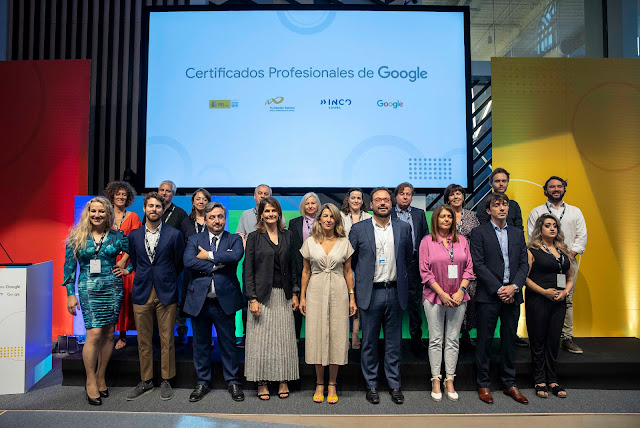 19 personas de pie en un escenario delante de una pantalla que dice "Certificados Profesionales de Google".