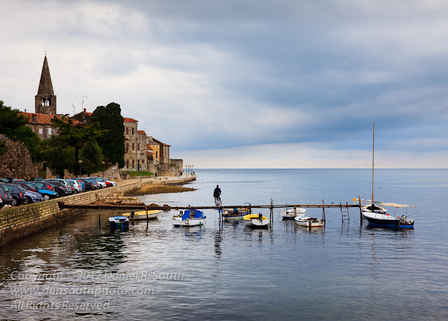a photo of a man with an umbrella standing on a dock in porec croatia
