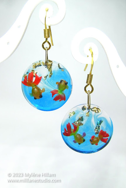 Round resin earrings swirled with blue and decorated with miniature goldfish