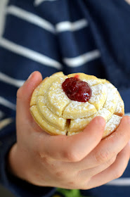 Fertig gebackene Rosenkrapfen aus dem Ofen – eine Kinderhand hält einen Krapfen.