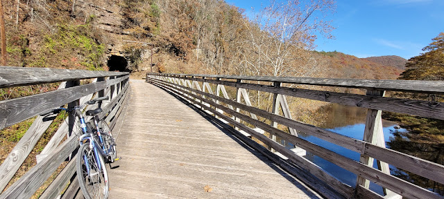 Wooden foot bridge leading to a dark tunnel entrance.