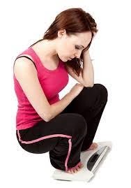 Weight Back. A woman squatting on a scale while she is sad