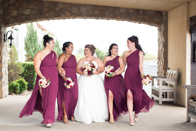  Cassie and Wyatt tied the knot at The Palace Event Center, in Yukon, OK, on July 15, 2017.   The venue’s magnificent wood entry doorways, outside rock façade, and adjacent country landscape provided the perfect backdrop to photograph the first look and pictures of the jovial wedding party.  The venue was spacious, which allowed us to sneak in a few pre-dressed shots of the girls in their “Wedding Tribe” t-shirts.     Cassie’s elegant, form-fitting, strapless, satin wedding dress overlaid with lace and sequins looked like it was made especially for her.  Wyatt was quite the Knight in Shining Armor dressed in his navy suit, grey vest, and burgundy tie.  The four beautiful bridesmaids wore matching full-length, flowing, burgundy gowns, slit at the knee.  Cassie’s gorgeous bouquet was composed of baby’s breath, peonies and ranunculus in rich hues of vibrant burgundy, red, pink, burnt orange, and yellow gold.  To add to the excitement of the day, their son had a special assignment—carrying the sign down the aisle that stated, “Daddy, Here Comes Our Girl.”     The venue’s grand ballroom, with it’s beautiful chandeliers and romantic lighting, was the perfect backdrop for the couple’s reception.  Candlelight, flowers, and twinkle lights adorned the nuptial stage, and after the vow exchange, Cassie and Wyatt participated in their first dance.  Guests were invited to enjoy the buffet, the cutting of the cake, and the toasts by the best man and bridesmaid.  Chairs were quickly removed from the dance floor, and while almost everyone spent the rest of the afternoon relaxing, dancing and socializing, there was a particularly fun-loving group of guests who decorated the bride and groom’s Jeep with sayings, crepe paper, and a car filled-to-the-brim with balloons!        Cassie stated that the best part of the wedding was being able to see so many family and friends at the reception having fun and enjoying themselves.  She said, “If we had it to do over, we wouldn’t do anything differently…it was perfect for both of us!”     It was a pleasure to capture the special moments of this memorable wedding day for Cassie and Wyatt, and we wish them a lifetime of love and happiness. 