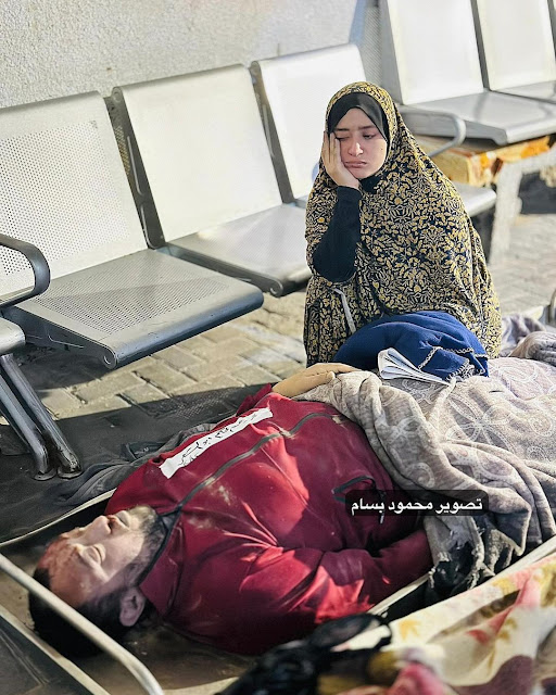 The widow looks to her husband in a way I can't describe it easily in Rafah by photographer Mahmoud Bassam