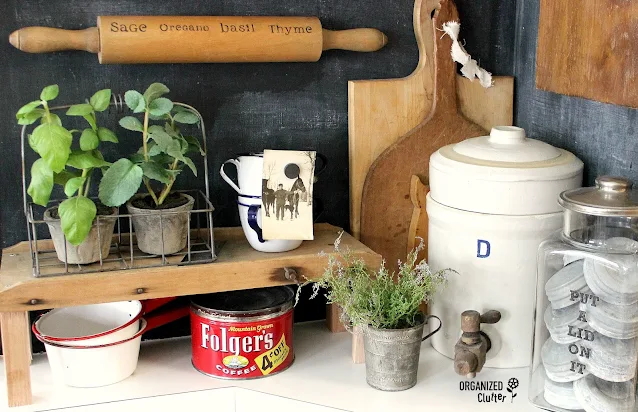 Photo of a herb name stenciled rolling pin hanging horizontally on a kitchen wall, and other farmhouse kitchen decor.