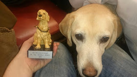 Kenzie y Pili con la estatuilla que le dieron la Asociación de perros guía por su décimo aniversario