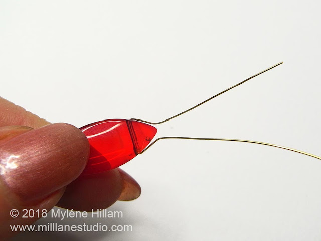 Wire strung through a top-drilled red dagger bead.