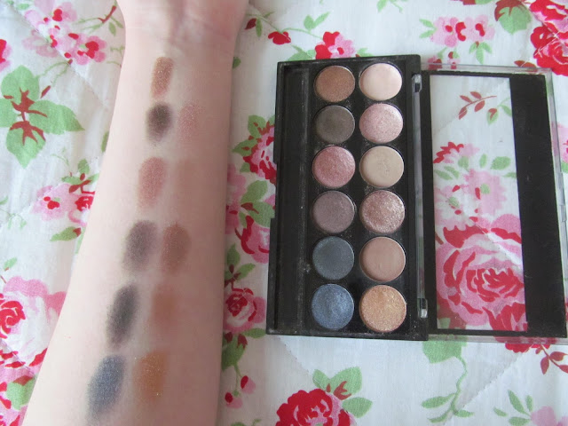 12 eyeshadow shades - cream, pale pink shimmer, dark pink shimmer, khaki, matte cream, shimmer denim blue, shimmer navy, deep purple/brown shimmer, matte light brown and shimmer gold - swatched on white forearm