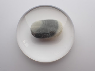 Domed resin paperweight containing a striped beach pebble