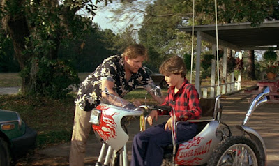 Gary Busey helps Corey Haim with his electric wheelchair in a movie still for the 1985 horror film Silver Bullet, 31 days of Halloween movie review
