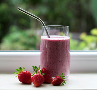 a berry smoothie with strawberries in front of the glass