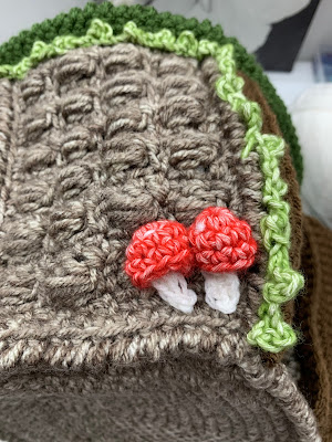 picture of a crocheted hut with mushrooms and vines