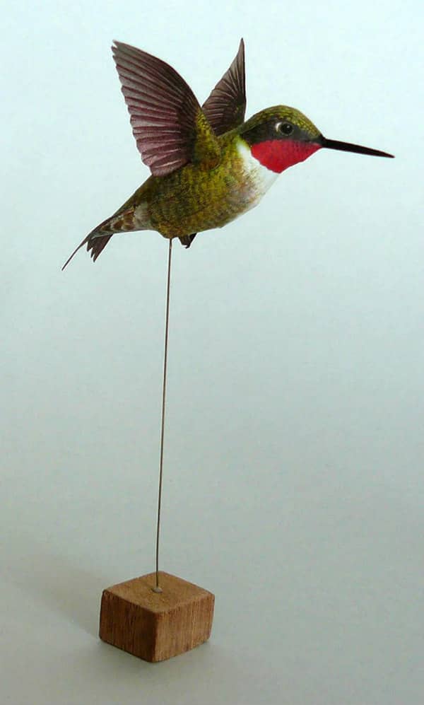 model of ruby-throated hummingbird with wings extended, placed on wire inserted into square wooden base