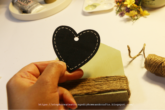 Hand holding heart embellishment near wooden house