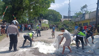 Petugas bersama warga menyingkirkan terigu yang berhamburan dari dalam truk maut yang menutupi Jalan Raya Cianjur-Sukabumi, Jawa Barat, Minggu (14/8/2022).