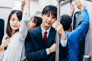 満員電車で暑さにぐったりとしている男女の写真