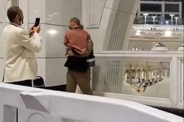 A Security officer at Makkah carries a Pilgrim to show him Holy Kaaba - Saudi-Expatriates.com