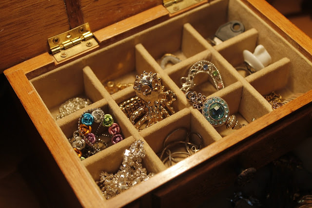 Wooden jewelry box filled with different types of jewelry pieces
