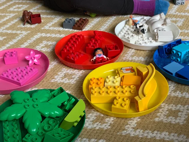 Coloured plates with coloured LEGO DUPLO pieces as sorted by a toddler for a development play idea