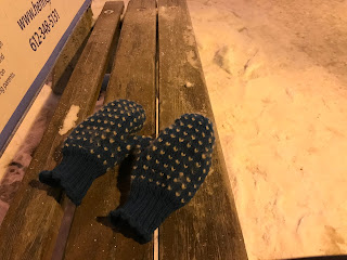 Thrummed mitten pair on a frostly bus bench.