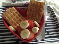 Red heart shaped dish with waffles, strawberries and sliced banana 