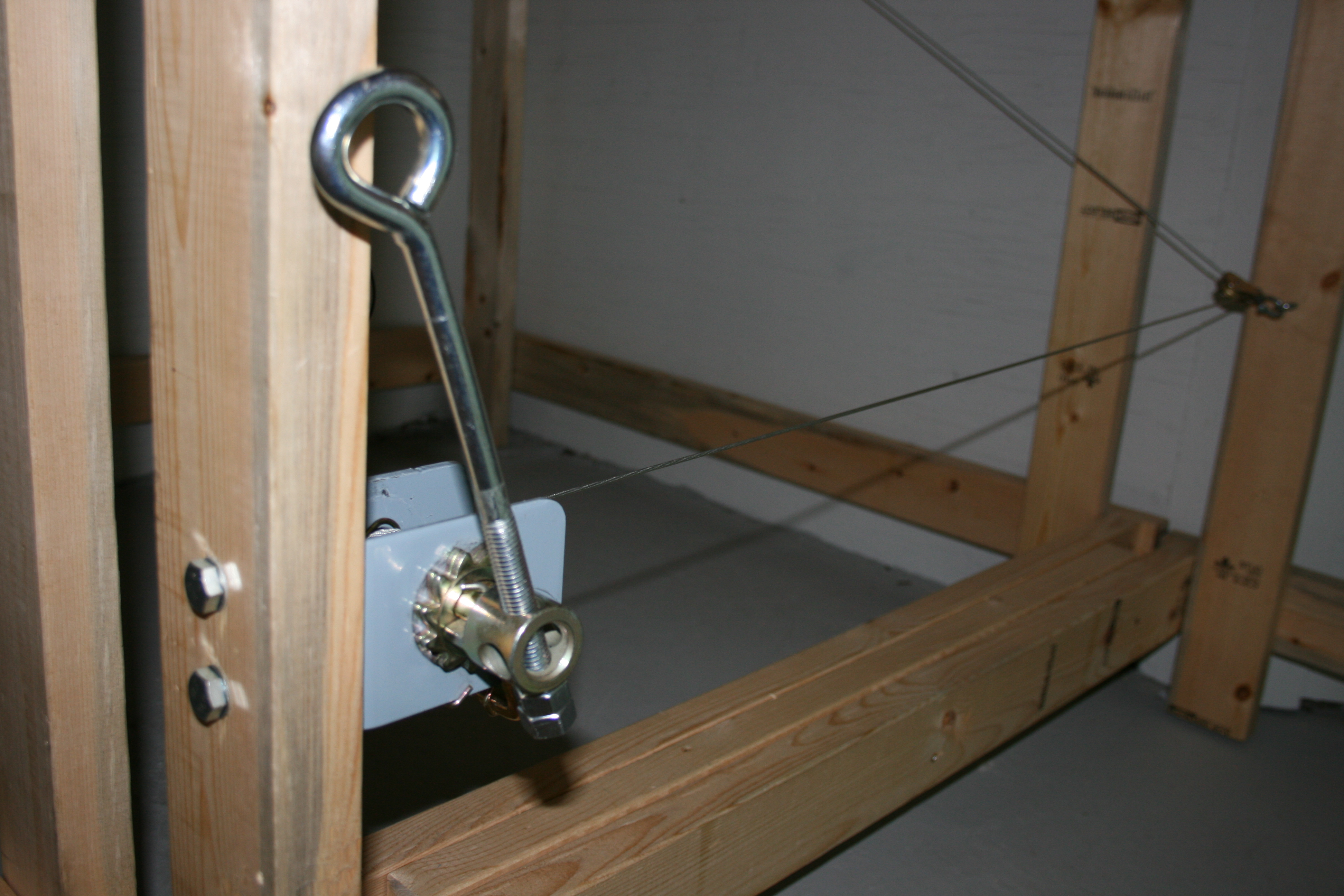 A large eye bolt being used as a crank handle on a locking winch below model railroad benchwork