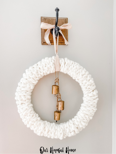 white knit wreath with brass bells