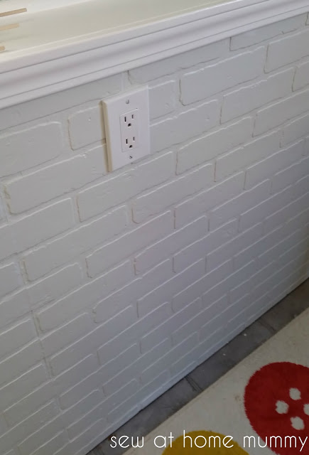 faux fake brick wall in a basement painted a matte white, love it. Love the contrast of the shiny trim and the outlets blend right into the wall!