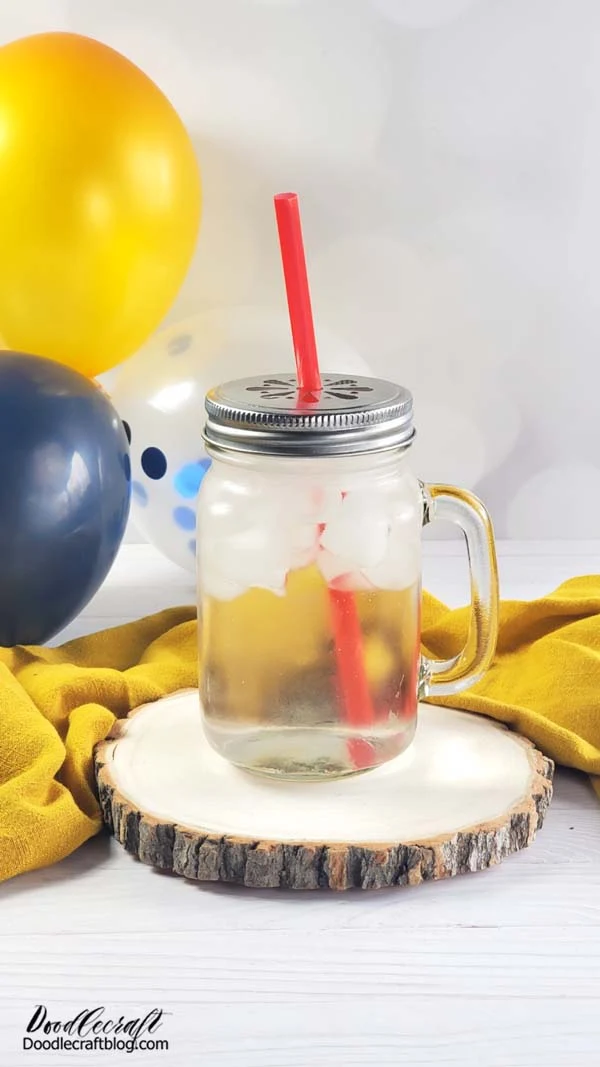 fresh clear citric acid lemonade drink in mason canning jar mug with red straw. Yellow and blue balloons in background reminiscent of Mr. Squeeze lemonade stand random encounter in Fallout 76