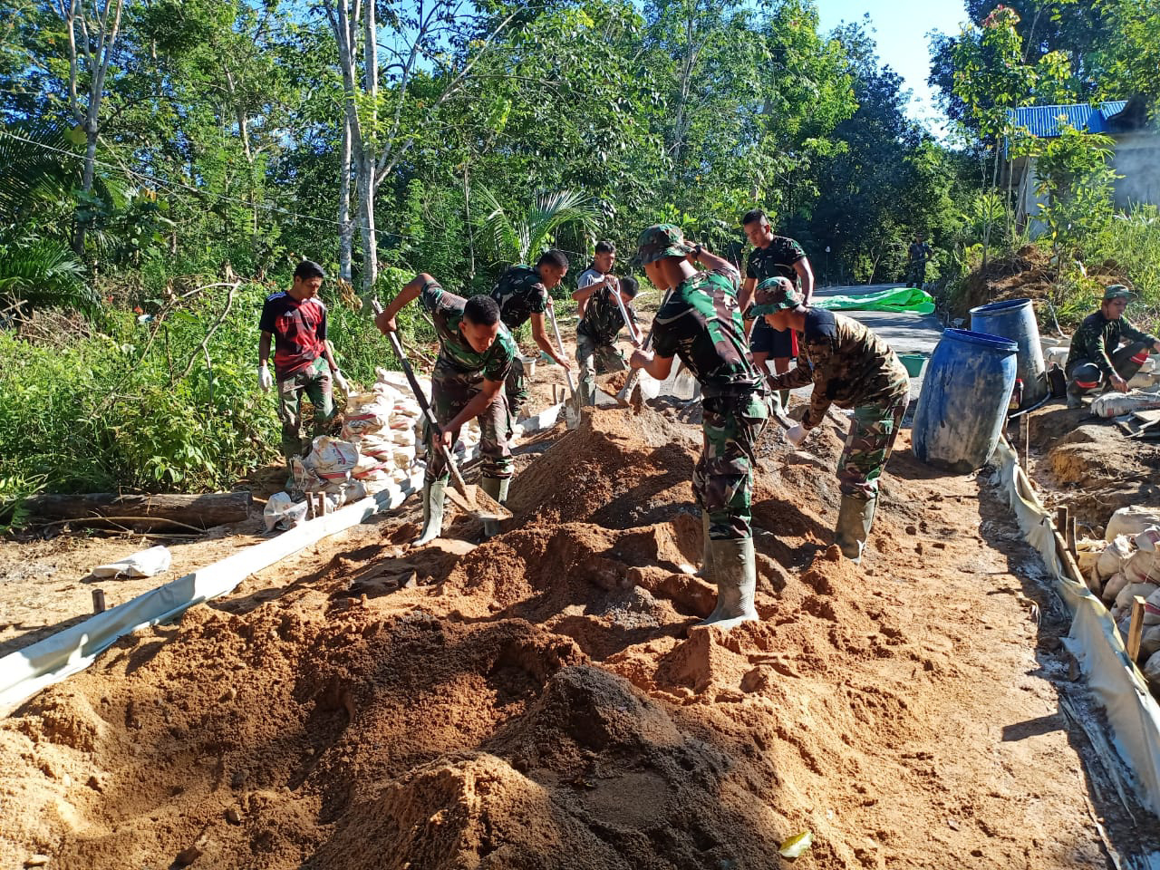 Skop Menari Ikuti Gerak Tangan Anggota Satgas TMMD Dalam Mengaduk Adonan Semen