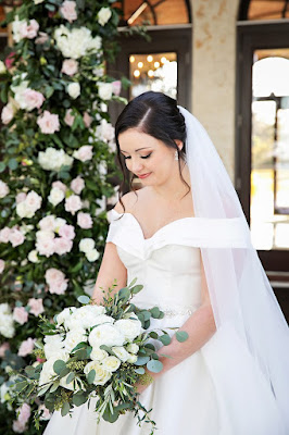 bride in white wedding dress looking at bridal bouquet