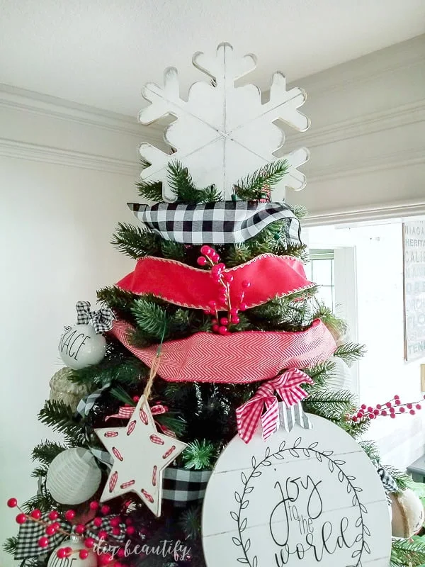 large painted white snowflake used as tree topper on farmhouse tree