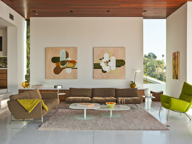 Picture of the sitting room with brown sofa and green chairs along with the paintings on the white wall