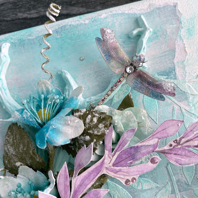 Aqua Dreams mixed media canvas created with: Prima aquarelle dreams flowers, paper, ephemera, acetate, art alchemy impasto paint; Reneabouquets butterflies, dragonflies, German glitter glass; Scrapbook.com buttercup stencil, cloud whip; Spellbinders opal gems