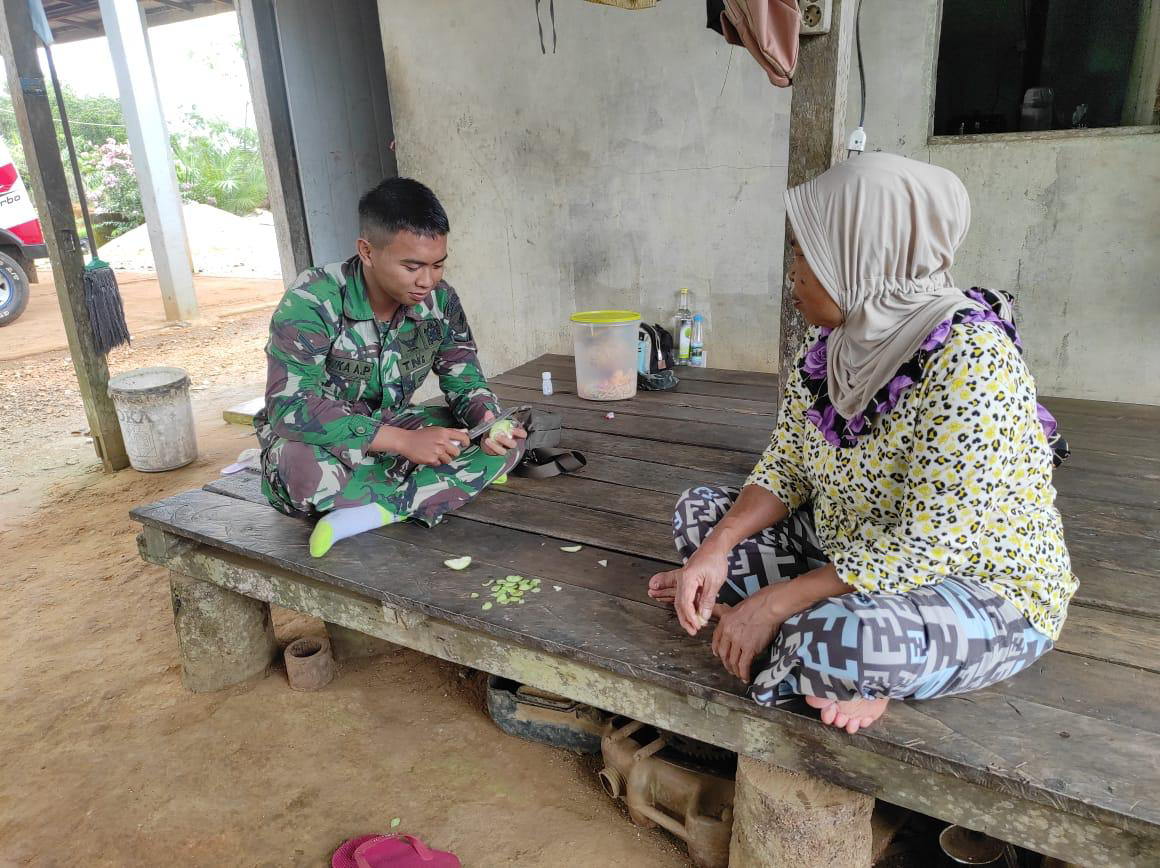 Anggota satgas TMMD bantu ibu asuh mengupas buah sekalian melaksanakan komsos