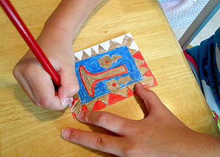 Tessa began by sketching a pattern for her illuminated letter. Then, she filled it in with Prismacolor colored pencils. Our set included a nice metallic gold. After diligently working on her letter for an hour, I took pity on Tessa's cramped hand and helped her with the final detail work. I used a metallic gold Jelly Roll pen to outline the gold sections. We took turns adding the gold dots.