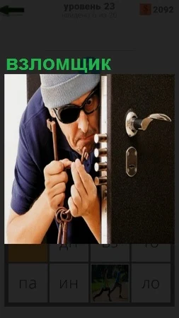 Мужчина взломщик подбирает ключ к замку на дверях