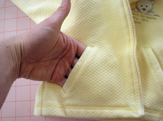 A functional welt pocket in an infant jacket