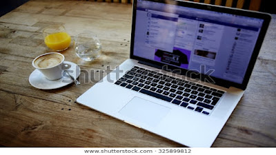 Brown top online work table with a computer, mug of creamy beverage, glass of juice and a glass of water.