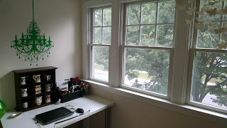 home office loft nook with one wall of windows, white desk, clear chair, green chandelier stencil.