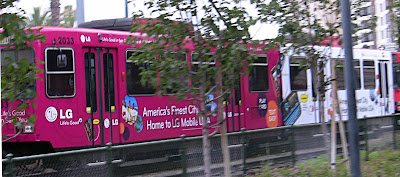 San Diego MTS trolley wrapped in a advertisement for LG phones.  The advert is hot pink and white