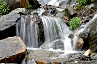 A covers of clouds with emerging sunlight greets you early morning with open arms sending you to a blissful world, forcing you to leave your worries behind and just emerge yourself in this heavenly scenery. Mahadev as the name suggests is the abode of Lord Shiva, at almost 19,000 feet above sea level in the Great Himalayan National Park in Banjar, Kullu and the awe inspiring natural rock-made Shivalingam which is almost 72 feet high is out of this world and mostly surrounded by a snowfield. Devotees of Lord Shiva can be seen trekking through the mountains to reach this hilly terrain all through July and August just to pay their respect as it is a famous pilgrimage for Hindus. Legend goes that Lord Shiva meditated here and the Pandavas used to visit this peak. It is also said that Bhim ki Bahi or the huge stone tablets with hieroglyphics were once noted by Bhim himself as he kept an account Pandava’s adventures.  Devoid of any form of grass, flowers, plants or tress all you will witness is lots of snow and huge rocks. Despite the fact that there are heavy snowfalls during the year the Shivalingam is never covered in snow. The heavy cloud movement around the hills is amazing and as visibility reduces you will find yourself engulfed with it, like some special effects had just been used. But then this is natural beauty at its best. Spending a day at the mountain top can be very exciting as well as thrilling. As morning turns to noon the clouds start to play hide and seek with the mountains changing colour every hour. During early hours and on a clear sunny day one can capture all the details on the mountains and the sudden changing weather is totally surprising and enjoyable too. You can actually stand on dry land and experience rain few hundred meters away while waiting to get there. Nothing can beat the sunset view as you enjoy the wonderful journey through the clouds. Those planning a trip can take the route from Nirmand or from the other side from Asru. The trek from Jaon Village takes about 38 kilometres to reach the Shrikhand Peak. Meticulous planning as well as prior advice from few adventure clubs will come in handy. To make your trek more comfortable and enjoyable, carry few energy bars, glucose or biscuits, water, walking stick, essential medicine as well as a torch. A guide or a coolie is also advised. En route you will come across small rickety bridges over gushing mountain streams near Barahati and an almost seven hours trek from here will take you to Thachru. Apple orchards between Jaon Village and Singh Ghat are inviting as you can always have a bite, of course taking permission from the owners. Though this stretch is quite steep through the forest followed by a long and a wide plateau with wild flowers, you can see the astounding views of the mountains among the clouds and the valley of flowers especially known for its rich herbal and medicinal plants. As you trek through the dark, eerie forests, guzzling waterfalls you may find yourself out of breath while climbing the final stretch to Shrikhand Mahadev as it is almost a vertical climb over the rocks. Other notable stops include the Kali Ghati, Bheem Dwari, Nain Sarovar and Parvati Bag, which finally takes you to the rocky mountain climb and into the clouds. There were no tree between Thacharu and Kaali Ghati and as you move forward all you can see ae the snow covered hills. As there are no water sources beyond Nain Sarovar, be sure to pack lots of water. This place is also famous for its rare and magnificent Brahmkamal flowers, and it is also said that the glacial lake was formed from a teardrop from Goddess Parvati’s eyes. Bheem Paudi or steps as the name suggests is full of huge rocks with various kinds of markings. View of the early morning Shrikhand Shivlingam is just striking and if you happen to reach on a full moon night the whole area glimmers in moonlight, hence enriching your experience of being there.Devotees of Lord Shiva would love to witness this natural marvel but those into adventure and trekking will be equally thrilled to visit this awesome as well as wondrous miracle.    