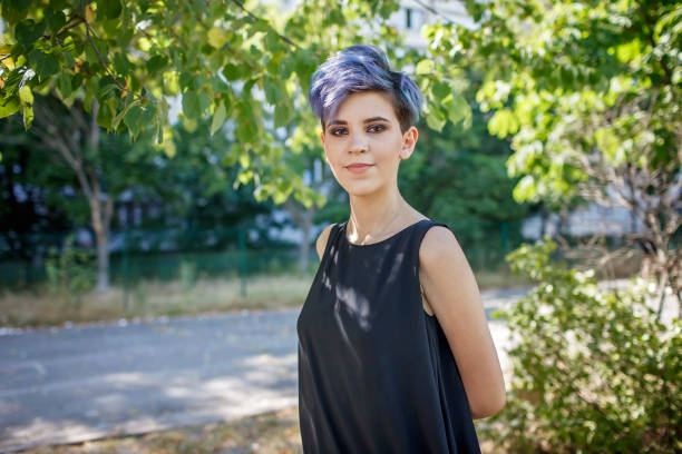 Stylish millennial with purple hair in black dress at outdoor graduation party