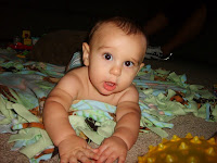 this is my nephew, he is laying on the ground and smiling while playing with his keyboard.