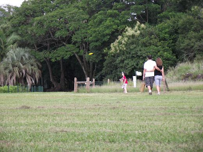 diversão em família: enquanto garoto joga frisbee, uma outra família caminha pelo gramado