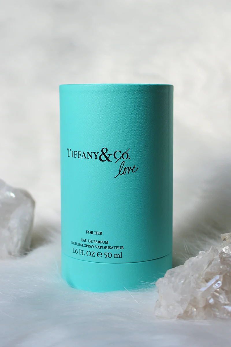 close-up studio shot of Tiffany & Co Love For Her Perfume tube on a white background surrounded by raw crystals