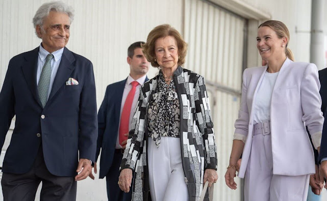 Queen Sofia wore a printed pattern tunic style wool cotton coat and a floral print pussy-bow silk blouse. White trousers