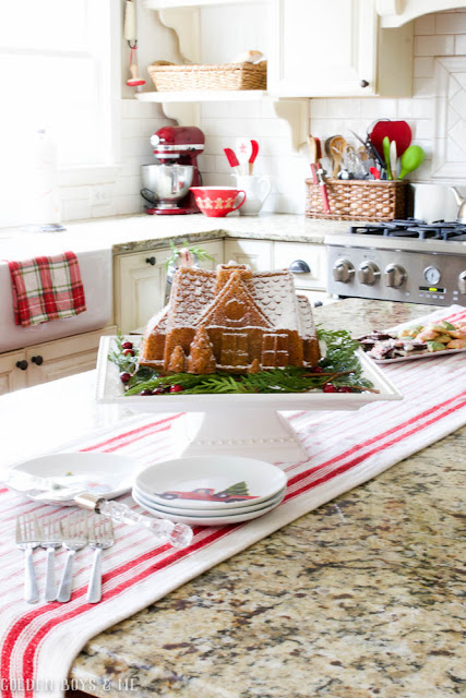 Gingerbread house cake displayed in farmhouse style kitchen with red and white Christmas decor